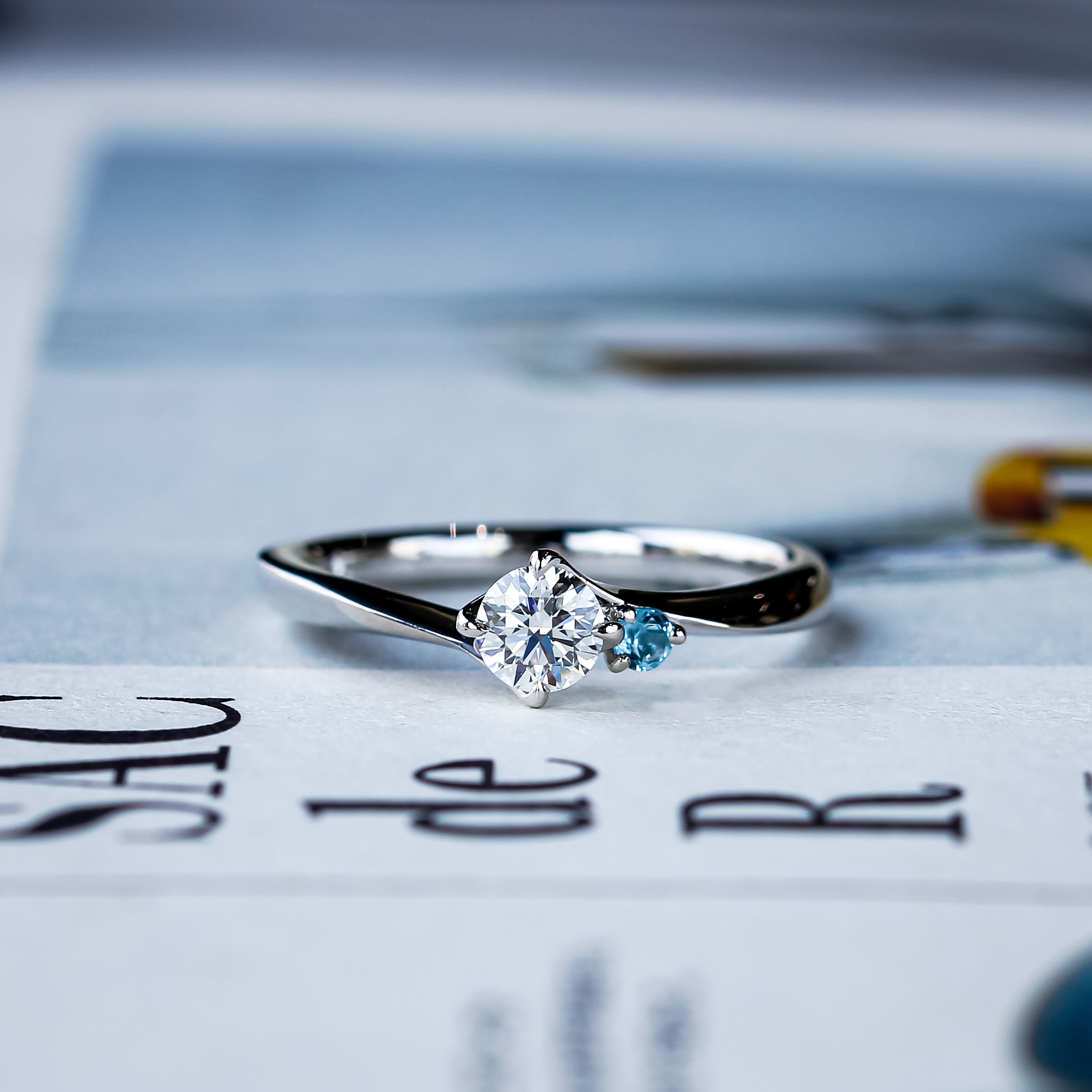 センターダイヤモンドの隣を飾る誕生石がシンプルながら想いがこもった婚約指輪（エンゲージリング）