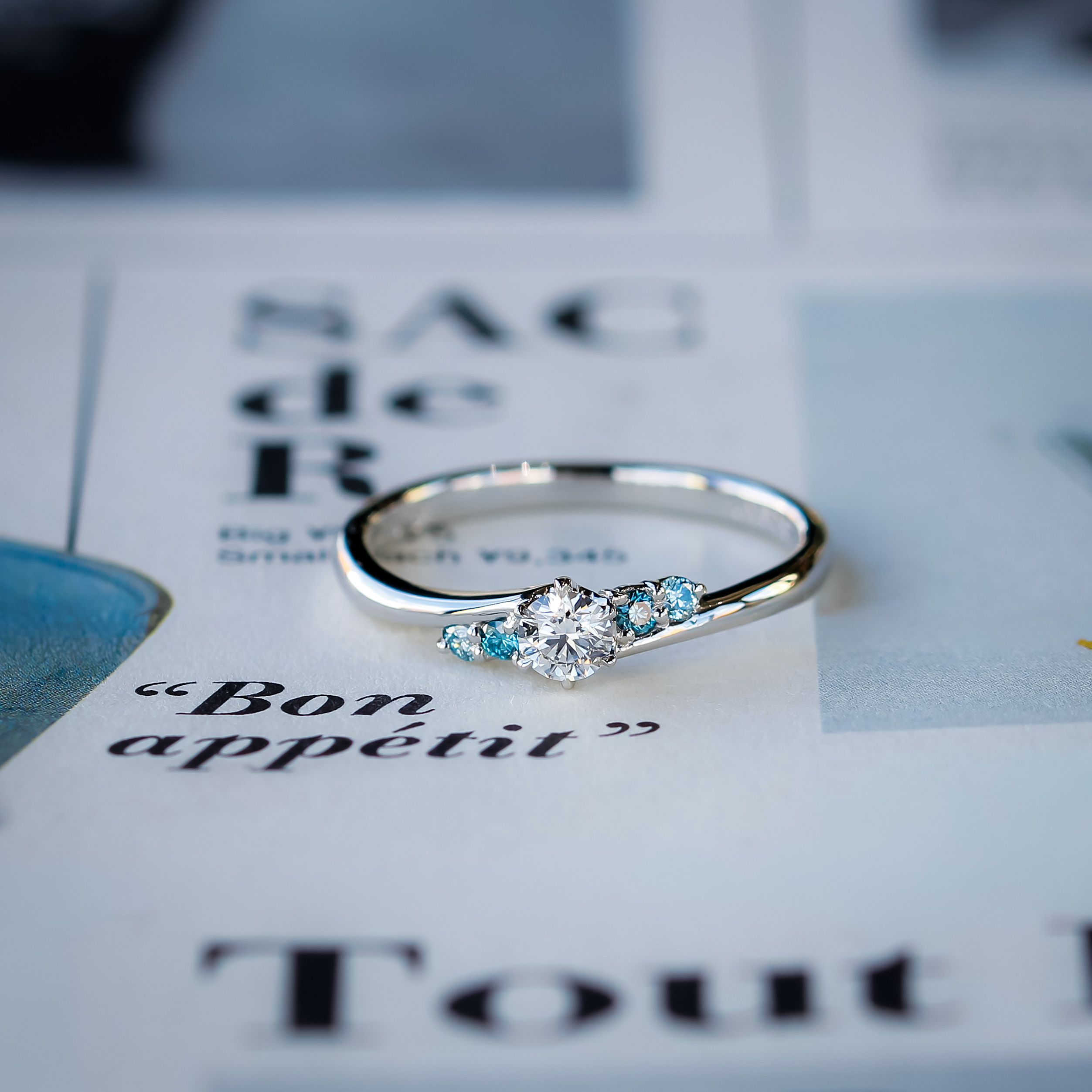 センターダイヤモンドの両サイドのメレダイヤモンドをブルーダイヤモンドにアレンジした婚約指輪